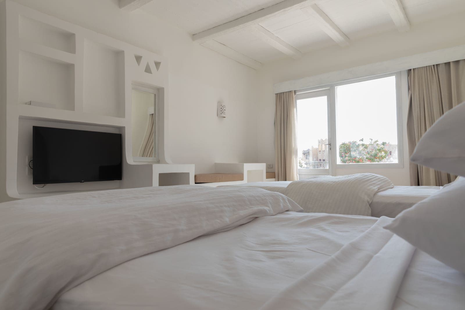 View across two Deluxe room beds toward the television and window
